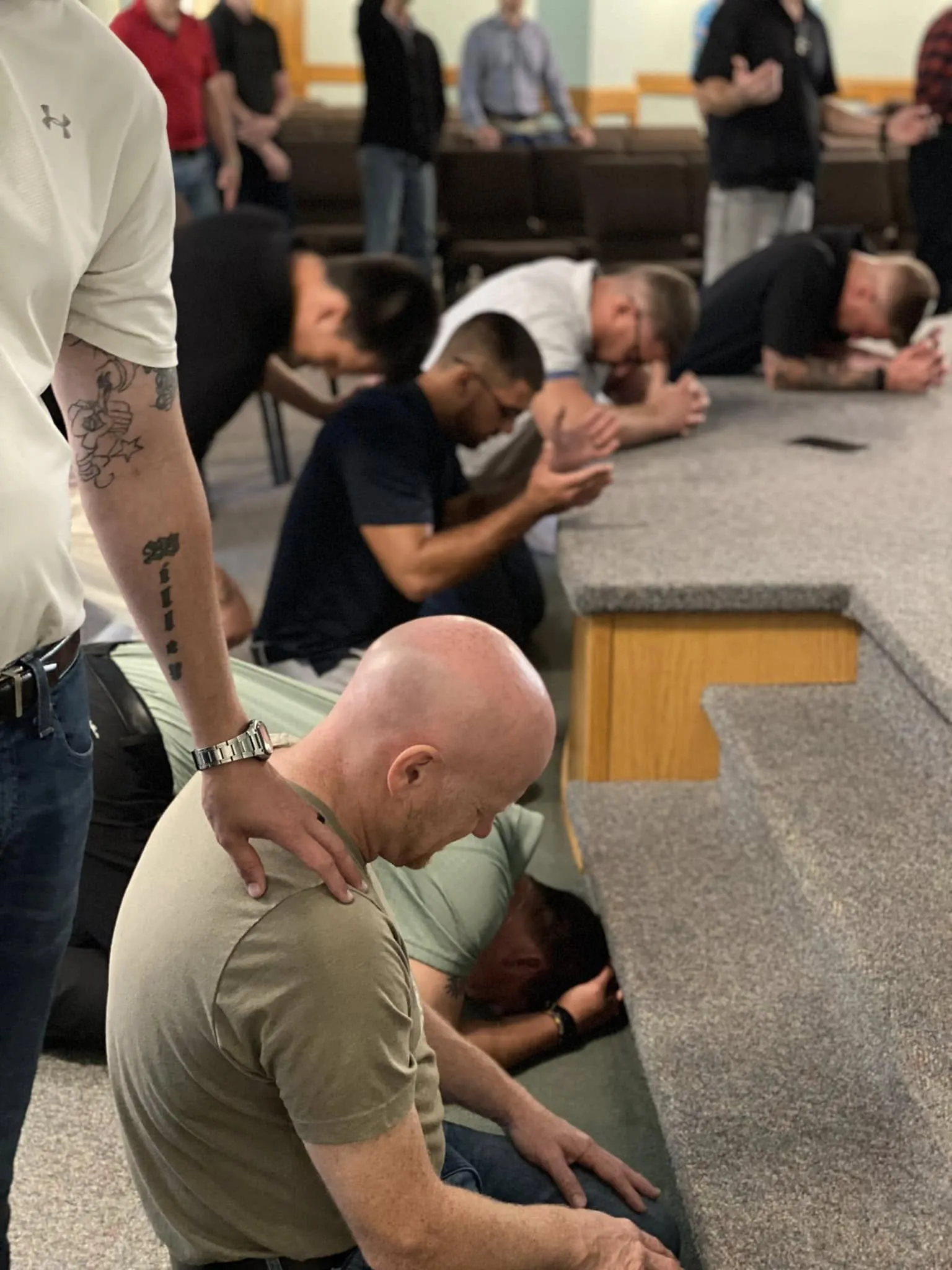 Men kneeling in prayer at the altar during a service